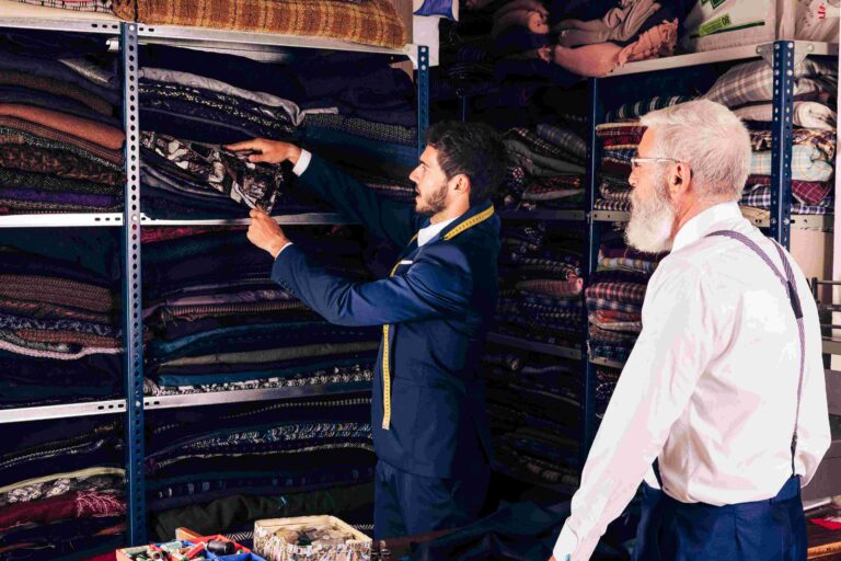 u3769-compressed_compressed_senior-man-looking-male-tailor-taking-fabric-from-shelf-workshop