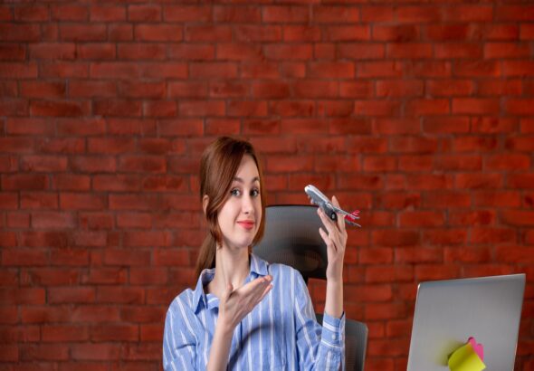 front-view-travel-agent-sitting-her-working-place-holding-toy-plane-agency-service-world-operator-assistant-map-global-ticket-managers-1
