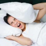 sad-girl-with-insomnia-young-asian-woman-lying-in-bed-cover-her-ears-with-pillow-cant-sleep-partner-snors-loud-noise-at-night-disturbing-her-free-photo-1