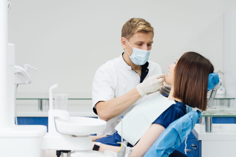 close-up-portrait-beautiful-young-lady-sitting-dental-chair-while-stomatologist-hands-sterile-gloves-holding-tooth-samples-1