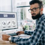 imgi_22_young-successful-seo-manager-sitting-at-workplace-2024-11-19-18-44-40-utc-1